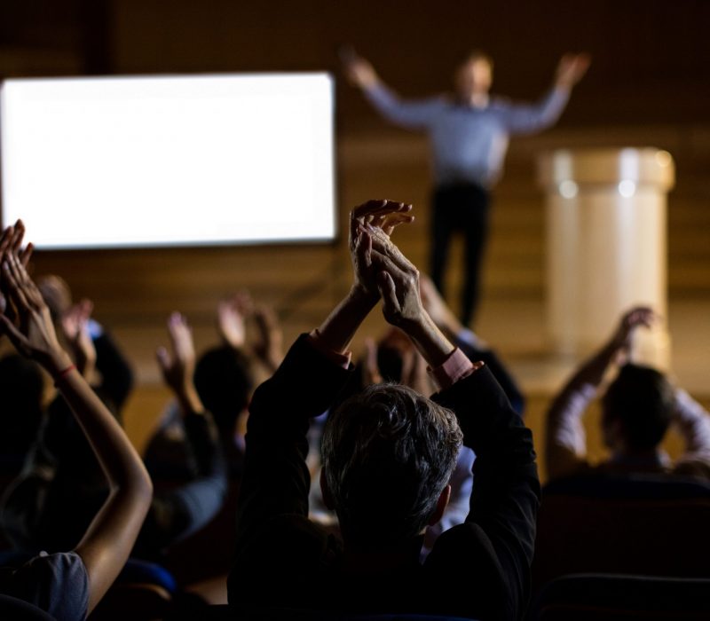 Audience applauding speaker after conference presentation at conference center